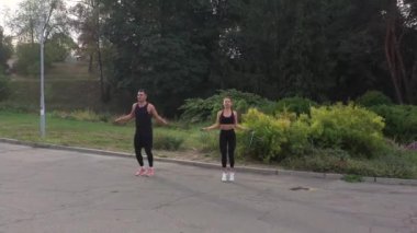 Dışarıda ip atlayan iki atlet. Sabah idmanında ip atlayan kadın ve erkeğin hava görüntüsü. Aktif kız ve adam halatla atlama antrenmanı yapıyor. Şehir parkında sabah sporu. Atletik insanlar atlıyor