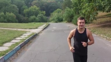 Açık hava parkında koşan aktif bir adam. Fitness koşucusu sağlıklı bir sabah. Park yolunda maraton antrenmanı yapan yakışıklı bir adam. Erkek koşucu dışarıda koşuyor. Erkek sporcuyla spor sabahı