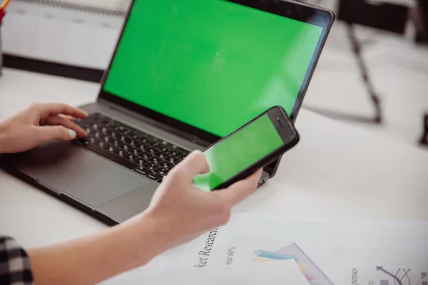 Yeşil ekranlı cep telefonu olan bir kadın el ele tutuşuyor. Taşınabilir laptop işyeri.