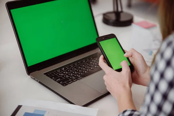 Рука жінки тримає мобільний зелений екран. Екран клавіш Chroma на ноутбуці Стокова Картинка