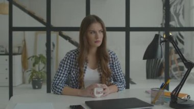 Elinde kupa olan bir kadın masada düşünüyor. Ciddi kadın işi düşünüyor.