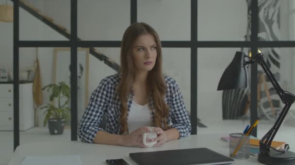 Mujer con taza pensando en la mesa. Mujer seria pensando trabajo — Vídeo de stock