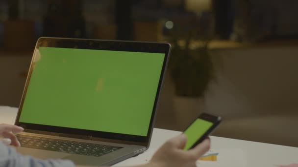 Feminino mão rolagem telefone com tela verde. Laptop e telefone com chave chroma — Vídeo de Stock