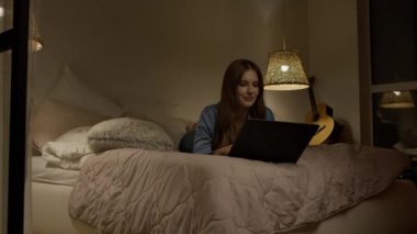 Evde dizüstü bilgisayar kullanan bir kadın. Yatak odasında dizüstü bilgisayar yazan neşeli kadın.