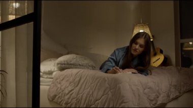 Pijamalarıyla not alan mutlu kadın. Kadın yazar yatakta notlar yazıyor.