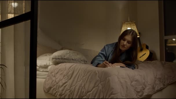 Lycklig kvinna antecknar i pyjamas. Kvinnlig författare skriva anteckningar i sängen — Stockvideo