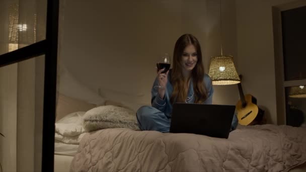 Mulher beber vinho no laptop on-line chamada à noite. Mulher alegre on-line namoro — Vídeo de Stock