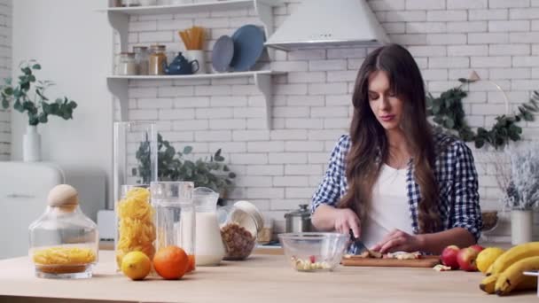 Vrouw snijdt appel voor fruitsalade in de keuken — Stockvideo