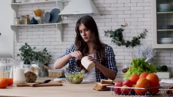 부엌에서 샐러드에 소금을 부는 여자. 현대식 주방에서 샐러드를 조리하는 여자 — 비디오