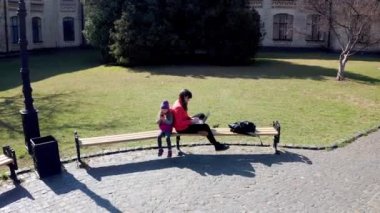 Anne dışarıda çocukla çalışıyor. Defter üzerinde çalışan çocuklu bir kız öğrenci