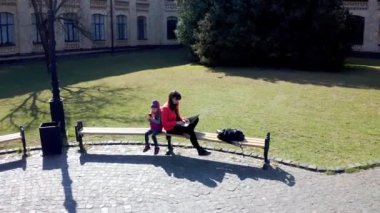 Kızı dışarıda dizüstü bilgisayarda çalışan sıradan bir kadın. Modern annelik