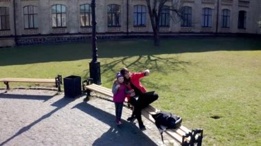 Annesinin parktaki bankta selfie çekerken görüntüsü. Anne ve çocuk.