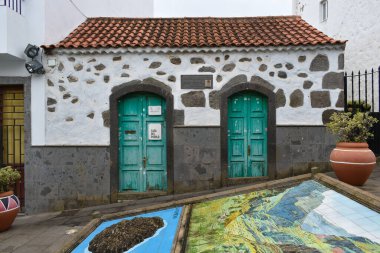 Firgas, İspanya, 10 / 10 / 2020: Yeşil boyalı ahşap kapılı beyaz ve gri taş ev.