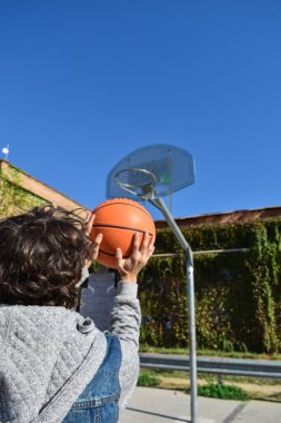 Basketbol kalesine top atan bir adam.