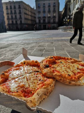 Lezzetli bir margarita pizzasının dikey çekimi sokakta servis edilen bir kutuda.