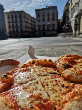 Lezzetli bir margarita pizzasının dikey çekimi sokakta servis edilen bir kutuda.