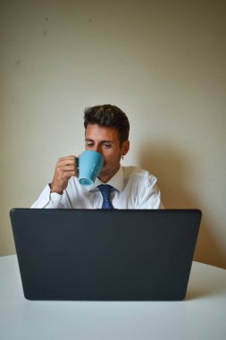 İşadamı bilgisayarın başında çalışırken kahve içiyor..