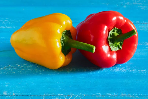 Red and yellow sweet peppers on a blue background