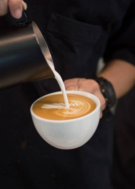 Coffee Latte is poured into a cup of Latte Art in a coffee shop. clipart