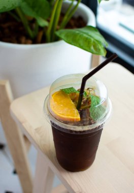 Kahve dükkanındaki ahşap masaya portakal suyu konmuş Espresso kahve fincanı..