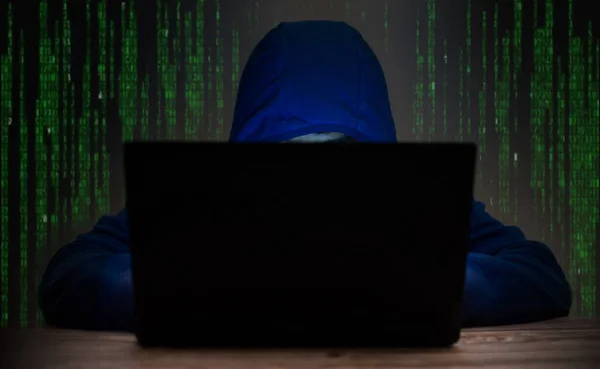 A man wearing a blue hooded shirt on a laptop computer Hacker concept to steal computer data