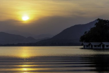 Akşam gökyüzündeki altın ışık ve göl kenarındaki güzel dağ manzarası..