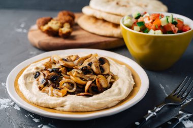 Kızarmış mantarlı humus, salatalık ve domates salatası, falafel ve pide. Karanlık arka plan. Orta Doğu yemeği