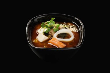 Somon ve kalamar ile Miso çorbası, çorba, wakame yosunu, shiitake mantarı, tofu peyniri, yeşil soğan, pırasa, susam tohumu. Japon yemeği. Siyah arkaplanda izole