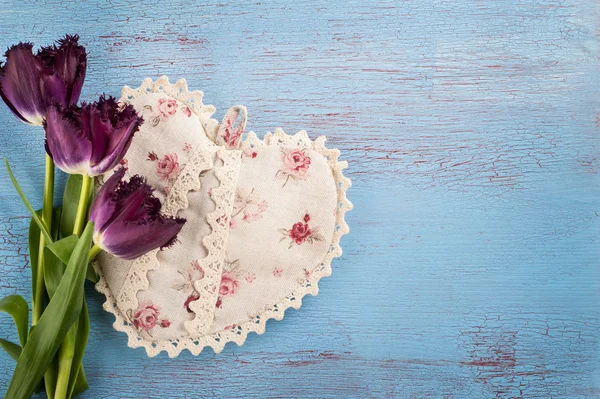 Tulips and heart on blue wood background