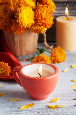 Kırsal arka planda kırmızı mum ve turuncu çiçekler. Metnin için kopyalama alanı olan tebrik kartı