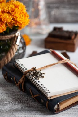 Boş bir defter ve rustik arka planda turuncu kasımpatı çiçekleri. Metnin için kopyalama alanı olan tebrik kartı