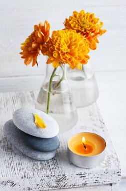 Turuncu kasımpatı çiçekleri çakıl taşları ve aroma mumu beyaz kırsal arka planda