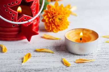 Kırsal arka planda kırmızı mum ve turuncu çiçekler. Kutlama için tebrik kartı