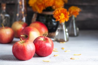 Kırsal masada olgun kırmızı elmalar ve sarı kasımpatı. Sonbahar dekoru 