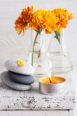 Turuncu kasımpatı çiçekleri çakıl taşları ve aroma mumu beyaz kırsal arka planda