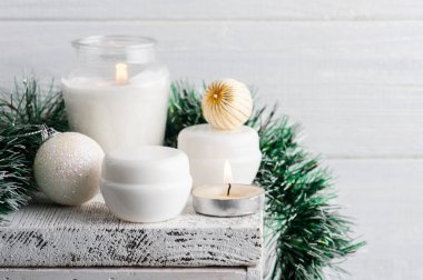 Noel kompozisyonu içinde beyaz kavanozlar ve yanan bir mum. Güzellik ürünleri için hazırlan.