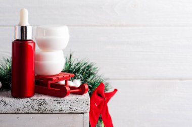 Kırmızı Noel kompozisyonu içinde beyaz kavanozlar ve yanan bir mum. Güzellik ürünleri için hazırlan.