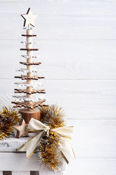Christmas decoration in Scandinavian interior with golden bow, star and wooden tree. Copy space for greeting