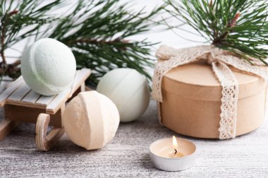 Hediye kutusu, yanan mum ve çam ağacı dallarıyla Noel SPA kompozisyonunda banyo bombaları.