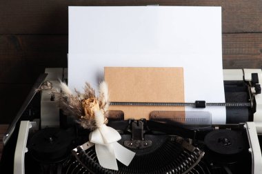 Daktilo kapanıyor ve çiçekleri zarfla kurutuyor. Sevgililer Günü konsepti, klasik tonlama ve kraft kağıdı