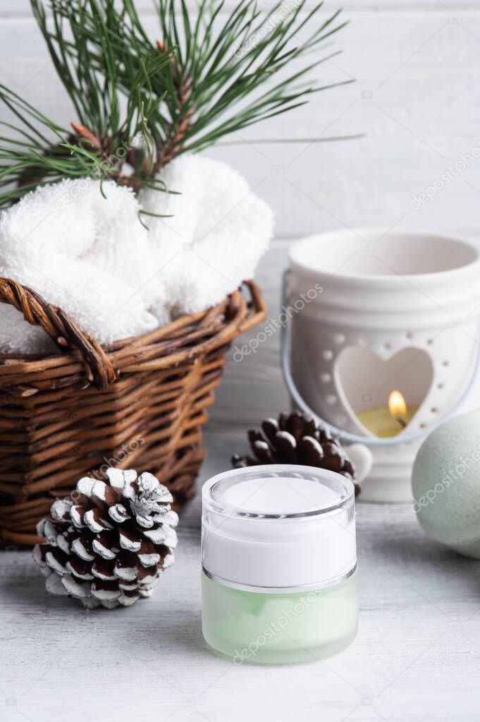 Beauty product in basket in Christmas SPA composition with pine tree branches and stars, lit candle