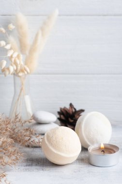 Banyo bombaları ve kuru çiçekli spa kompozisyonu tek renkli arka planda. Mum ve beyaz çakıl taşlı havlu. Bir kişi için sıcak taş masaj terapisi. Güzellik tedavisi ve rahatlama 