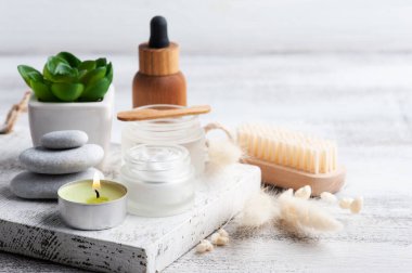 Kremalı kozmetik kavanoz, nemlendirici vücut losyonu ve ahşap arka planda gerekli yağ. Çevre dostu ambalajlı doğal organik spa