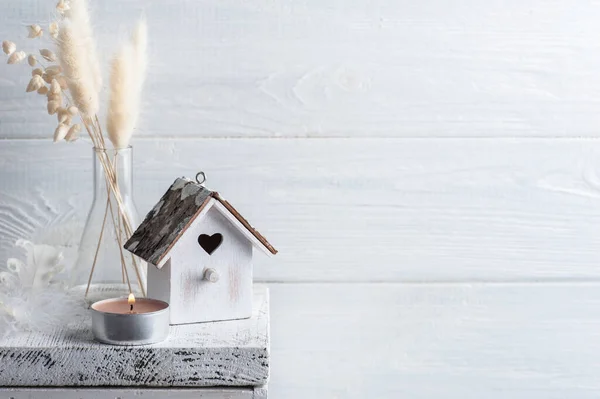 Home decor in Scandinavian style with pampas grass dry flowers on rustic background in monochrome style. Scented candles and birdhouse with copy space