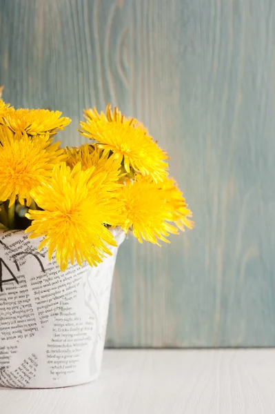 Paardebloemen in een pot op witte blauwe houten achtergrond — Stockfoto