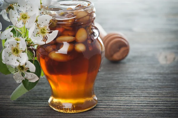 Honig im Glas mit Nüssen auf einem Holztisch — Stockfoto
