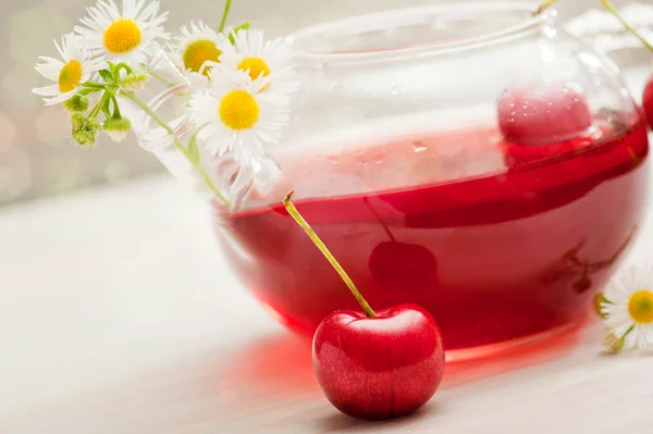 Tee aus roten Früchten in einer Glaskanne auf Holzgrund — Stockfoto