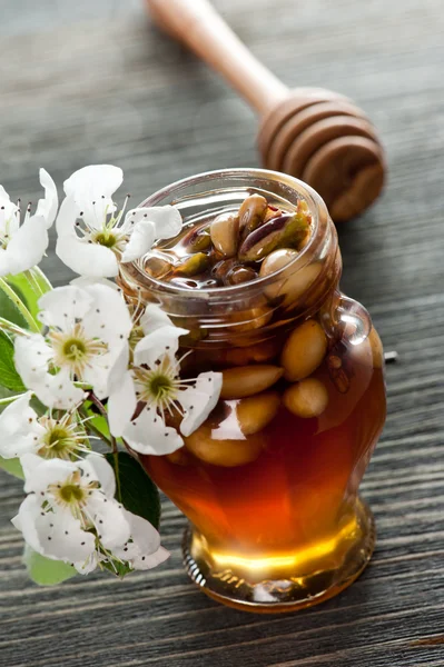 Honey in a jar with nuts on a wooden table — Stock Photo, Image