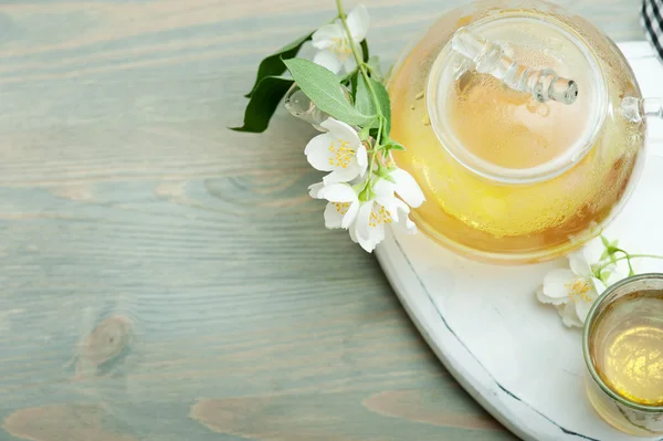 Jasmine tea in a glass tea pot on blue wooden background — Stock Photo, Image