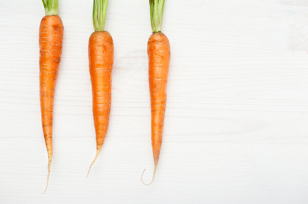 Raw carrots on white wooden table 